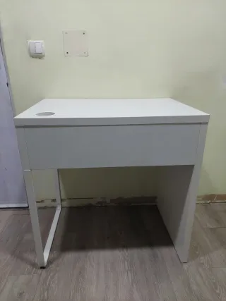 Escritorio blanco con cajón y silla.