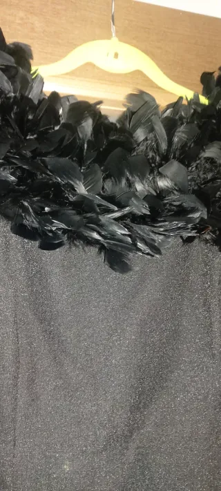 Vestido de fiesta negro con plumas y estola.