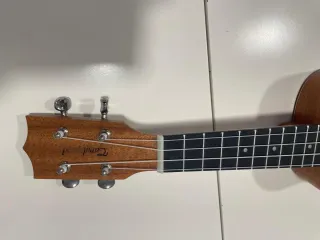 Ukelele marrón con funda y accesorios