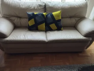 Sofá de piel beige con cojines