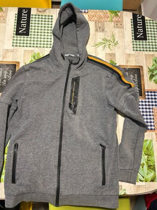 Sudadera gris con cremallera y detalles dorados