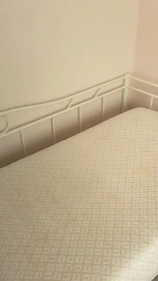 Cama individual de forja con supletoria debajo.