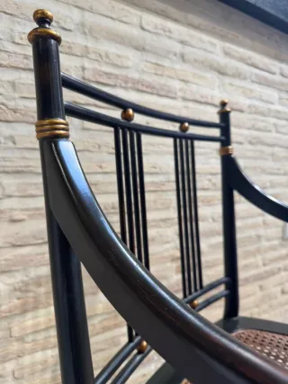 Silla negra con asiento rejilla y detalles dorados