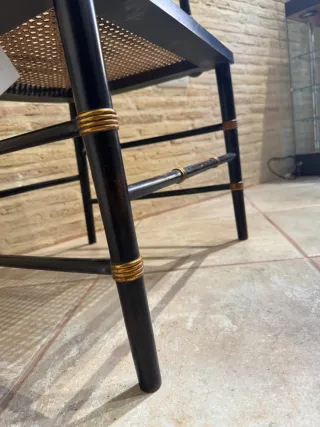 Silla negra con asiento rejilla y detalles dorados