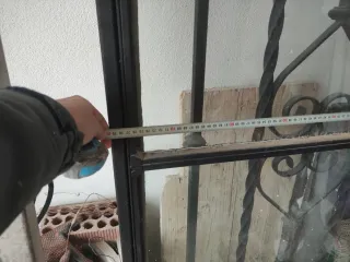 Puerta de forja con diseño y rejas de ventana.