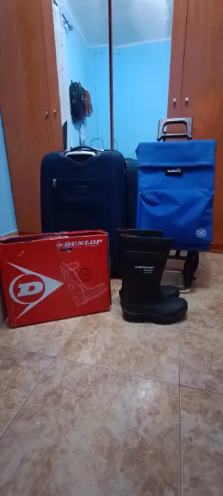 Carro de compra, maletas y botas de agua.