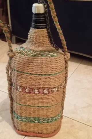 Botella antigua con asa, tapón y forrada.