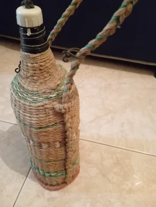 Botella antigua con asa, tapón y forrada.