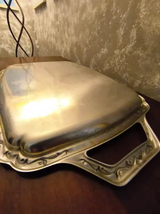 Vassoio da portata in metallo con manici decorati.