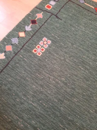 Alfombra de lana verde con diseño multicolor