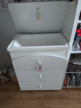 Mueble cambiador blanco con corazón rosa.