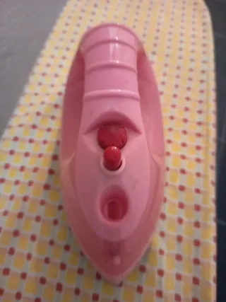 Plancha de juguete rosa y tabla de planchar.