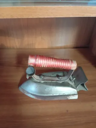 Plancha antigua de metal con mango rojo