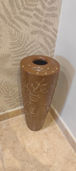 Jarrón decorativo marrón con detalles dorados.