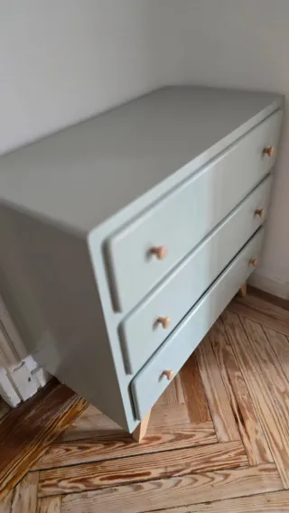 Cómoda de madera con tiradores de madera clara.