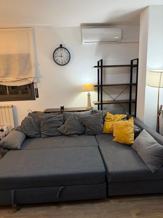 Divano letto grigio con cuscini gialli