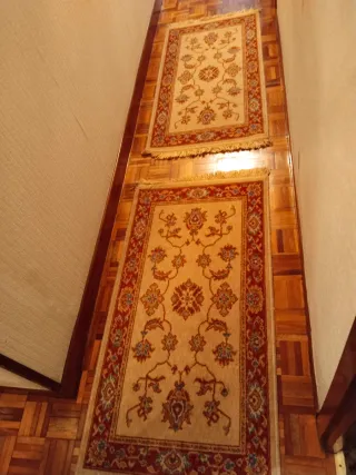 Dos alfombras beige y roja con diseño floral