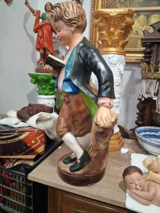 Niño de cerámica leyendo libro