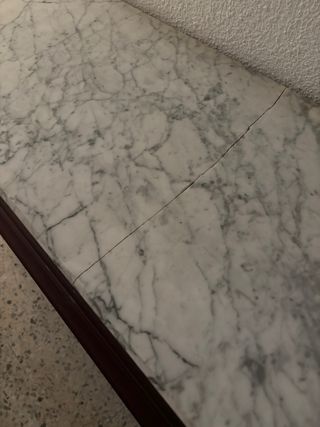 Mueble madera con encimera mármol. Está partida po