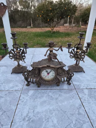 Reloj de mesa antiguo con dos candelabros.
