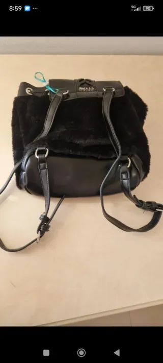 Mochila negra con pelo por fuera.