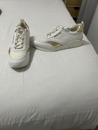 Zapatillas deportivas blancas y doradas