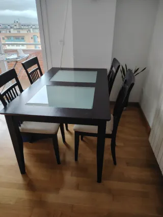 Mesa de comedor de madera y cristal y sillas.