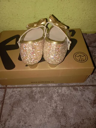 Zapatillas doradas con brillos y lazo