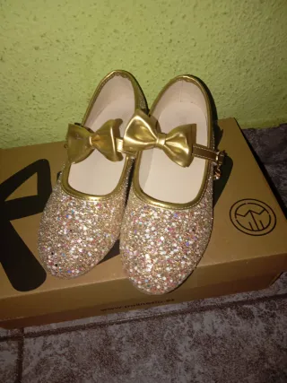 Zapatillas doradas con brillos y lazo