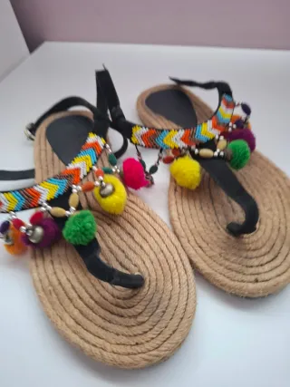 Sandalias con pompones y abalorios.