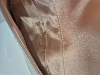 Bolso de mano beige con adorno metálico
