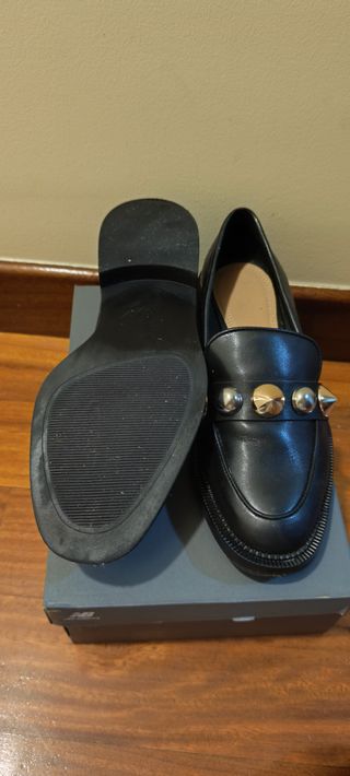 Zapatos negros planos con tachuelas doradas