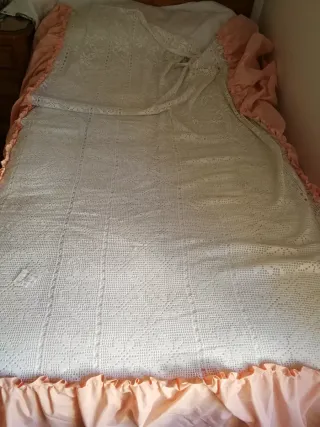 Colcha blanca d ganchillo con volante d tela rosa.