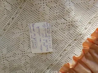 Colcha blanca d ganchillo con volante d tela rosa.