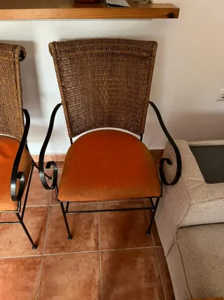 Sillas de metal y mimbre con cojín naranja