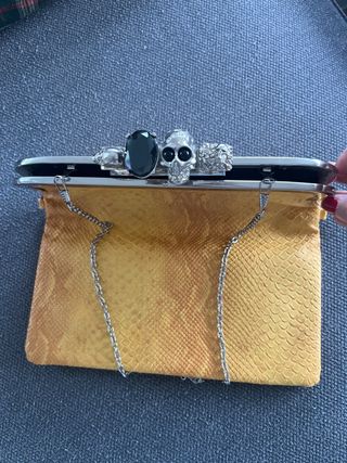 Bolso de mano con calaveras y joya.