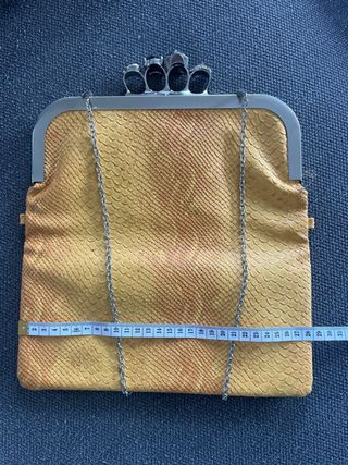 Bolso de mano con calaveras y joya.