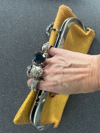 Bolso de mano con calaveras y joya.