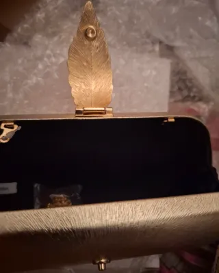 Bolso de mano dorado con hoja