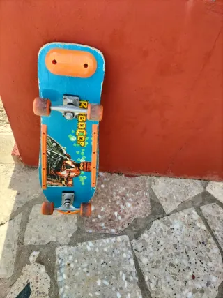 Monopatín azul con ruedas naranjas