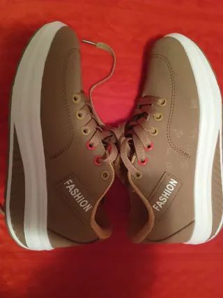 Zapatillas deportivas marrones con suela blanca.