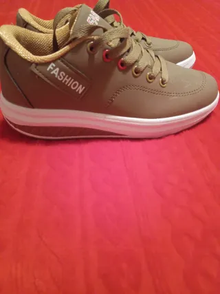 Zapatillas deportivas marrones con suela blanca.