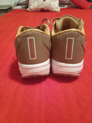 Zapatillas deportivas marrones con suela blanca.