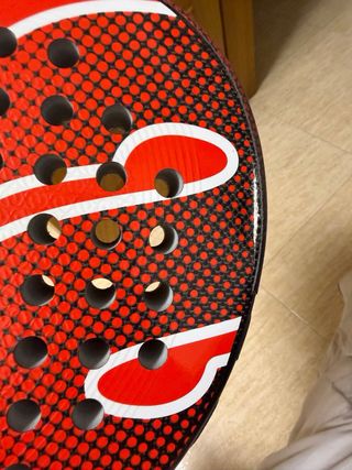 Pala de pádel roja con puntos negros