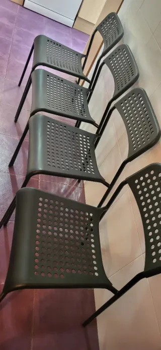 Mesa redonda blanca con 4 sillas negras de plástic