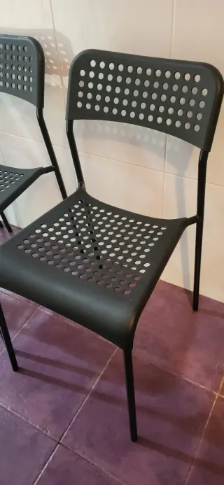 Mesa redonda blanca con 4 sillas negras de plástic