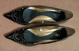 Zapatos charol negro con pespunte en blanco.