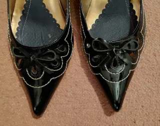 Zapatos charol negro con pespunte en blanco.