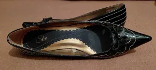 Zapatos charol negro con pespunte en blanco.