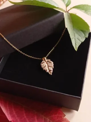 Colgante de cerámica y oro con forma de hoja.